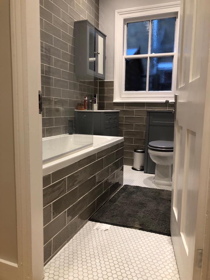 Bathroom with dark tiles, a bathtub and natural light