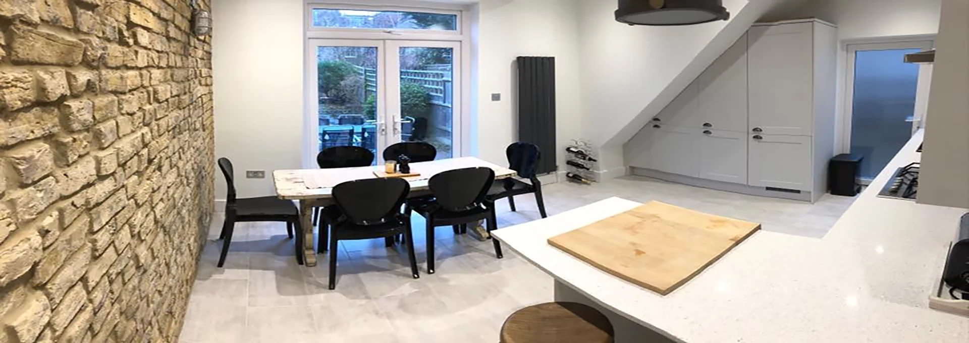 Light-filled kitchen and dining space with an exposed brick wall